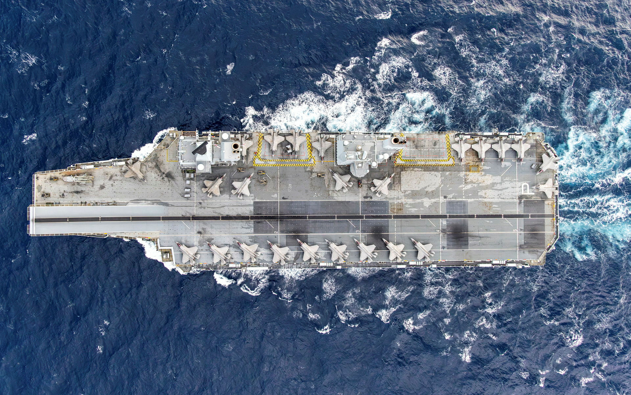 Pictured: 21 Nov 2025 – View of the 24 F-35B Jets embarked onboard the Flight Deck of HMS Prince of Wales. As part of the United Kingdom Carrier Strike Group Full Operating Capability, the largest fifth-generation Carrier Air Wing has ever been embarked on HMS Prince of Wales. 24 F-35B Jets on deck, in support of NATO on NEPTUNE STRIKE 25-4. This proves NATO’s willingness and readiness to act in support of allied nations’ peace and security. Italian F-35Bs have been on board HMS Prince of Wales for NEPTUNE STRIKE, an enhanced vigilance activity, as part of Operation HIGHMAST, proving interoperability and interchangeability between the two nations. The Joint Carrier Air Wing has conducted NEPTUNE STRIKE, showcasing the UK and Italian ability and willingness to work together on behalf of NATO in the Mediterranean and beyond. Led by the UK flagship HMS Prince of Wales and involving a dozen nations, the eight-month mission – known as Operation HIGHMAST – is reaching its final stages. After operations across the Indo-Pacific over the last five months, the task group has returned to the Mediterranean for further multinational exercises before making its homeward voyage. The goal of Operation HIGHMAST is to reaffirm the UK’s commitment to the security of the Mediterranean and Indo-Pacific region, demonstrate collective resolve with our allies and showcase British trade and industry. Over the course of the deployment, upwards of 4,500 British military personnel have been involved, including nearly 600 RAF and 900 soldiers alongside 2,500 Royal Navy sailors and Royal Marines.