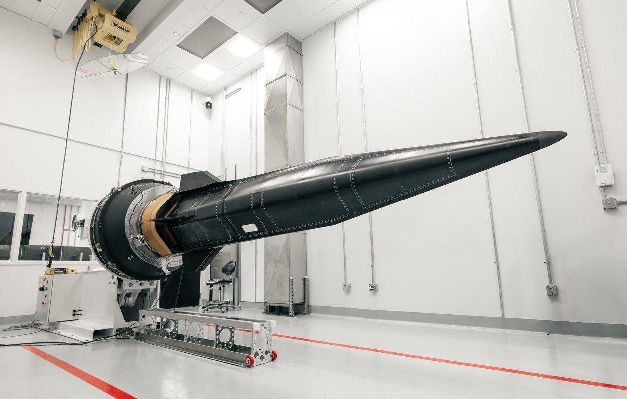 A hypersonic vehicle test article mounted on a ground-based test rig inside a laboratory, featuring a long, pointed nose and aerodynamic control surfaces.