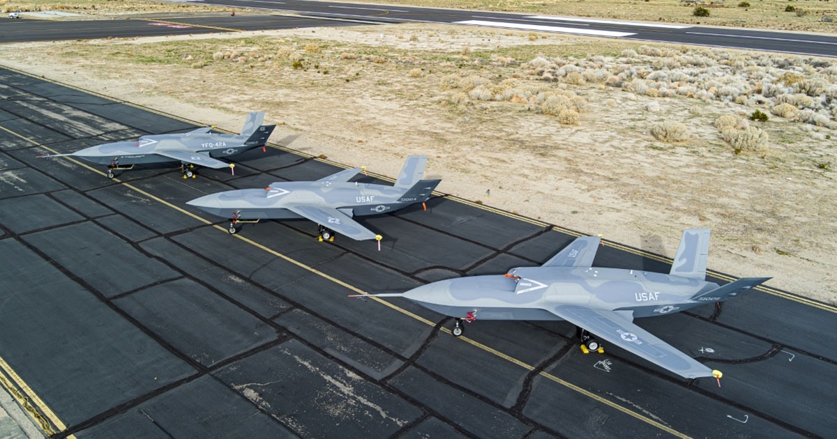 Three General Atomics unmanned aircraft lined up on a runway at a desert airfield, painted in U.S. Air Force markings.