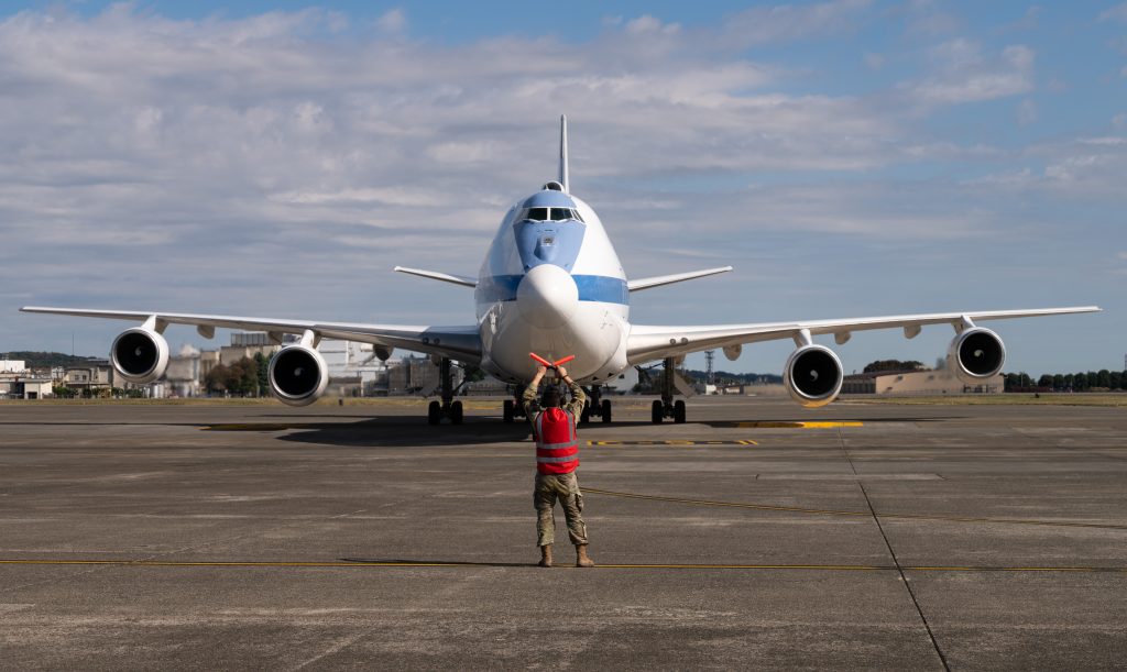 A U.S. Air Force Airman marshals a U.S. Air Force E-4B Nightwatch through Yokota Air Base