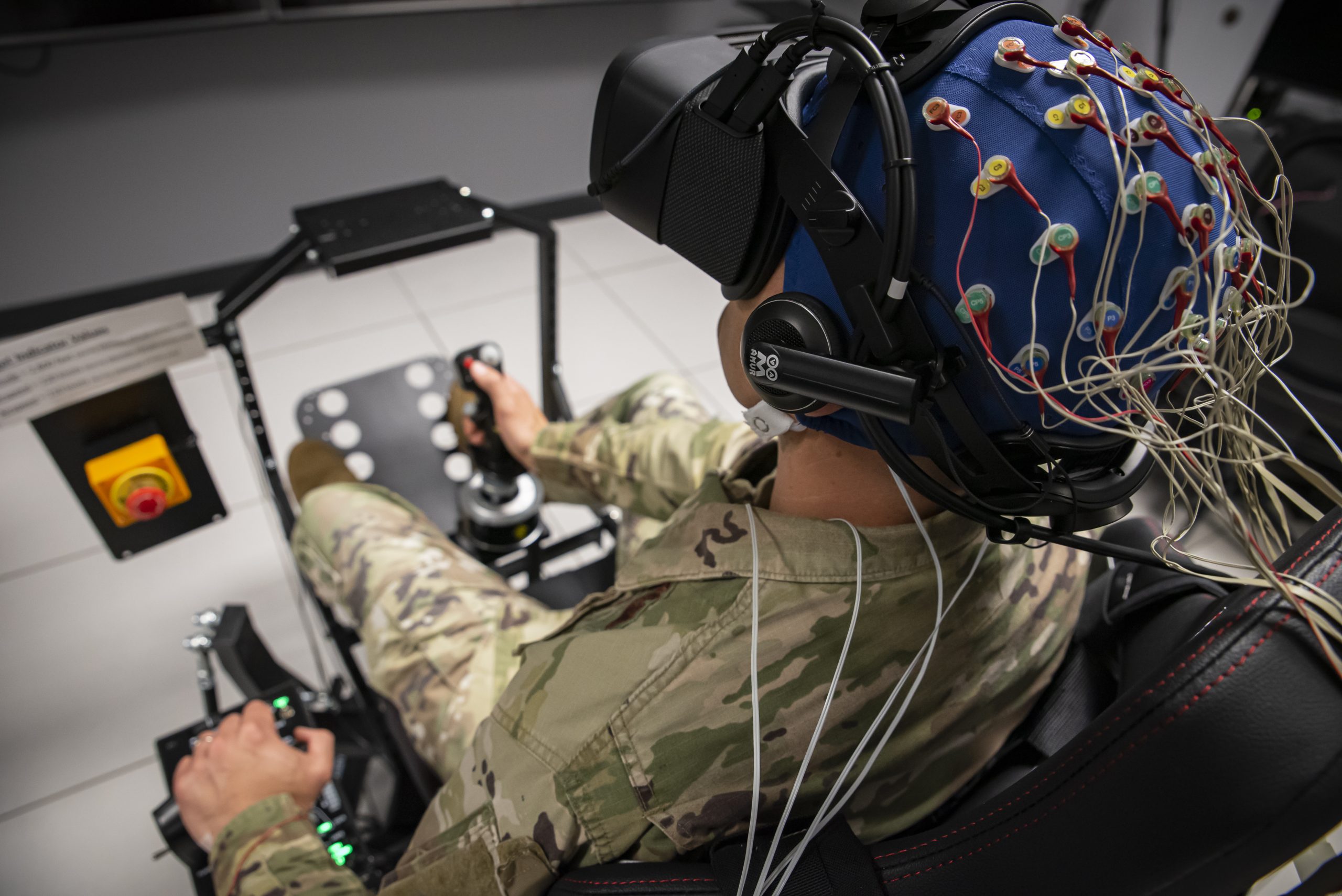 Master Sgt. Bradley Blair, senior enlisted leader, U.S. Air Force School of Aerospace Medicine, or USAFSAM, Office of the Dean, completes an exercise in a T-6A Texan II virtual reality flight simulator while wearing a cap that measures brain activity after applying a cervical transcutaneous vagus nerve stimulation, or ctVNS, device to his neck during a test at the Human Universal Measurement and Assessment Network Laboratory at Wright-Patterson Air Force Base, Ohio, May 19, 2023. Researchers with the Air Force Research Laboratory, or AFRL, Human Effectiveness Directorate developed a military-grade ctVNS device to enhance cognitive performance in Airmen and Guardians, specifically to accelerate training, mitigate fatigue and enable decision superiority. USAFSAM and the Human Effectiveness Directorate are two mission units that comprise AFRL’s 711th Human Performance Wing. (U.S. Air Force photo / Richard Eldridge)