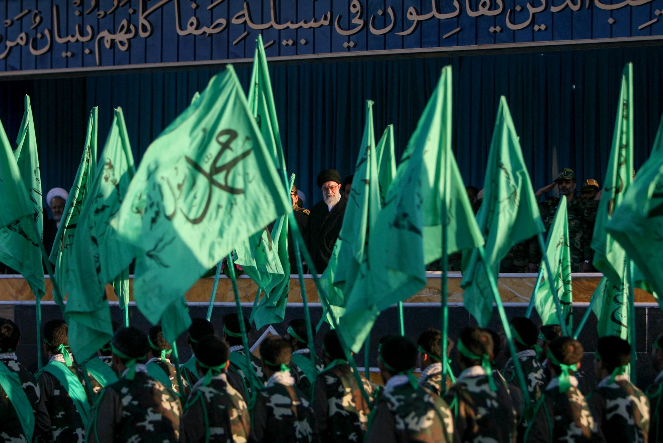 Iranian soldiers carrying green flags march past a reviewing stand holding Iranian Supreme Leader Ayatollah Ali Khamenei and senior military commanders during a ceremony in Shahrud, Iran, on November 11, 2006. Iranian Supreme Leader Ayatollah Ali Khamenei attended the joint military ceremony at the base of the 58th Takavar Division to review provincial armed forces units and observe tactical training exercises. (Photo by Hossein Fatemi / Middle East Images via AFP)