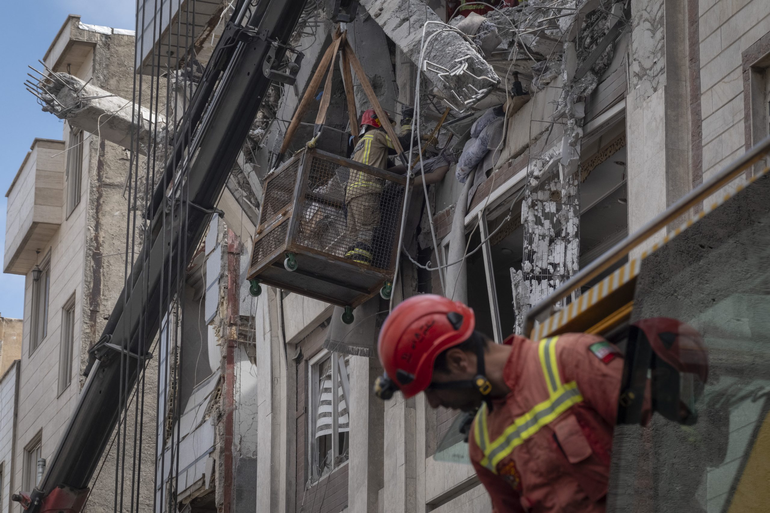Iranian firefighters work to recover the body of an Afghan woman from the ruins of a residential building in Tehran, Iran, on March 27, 2026.