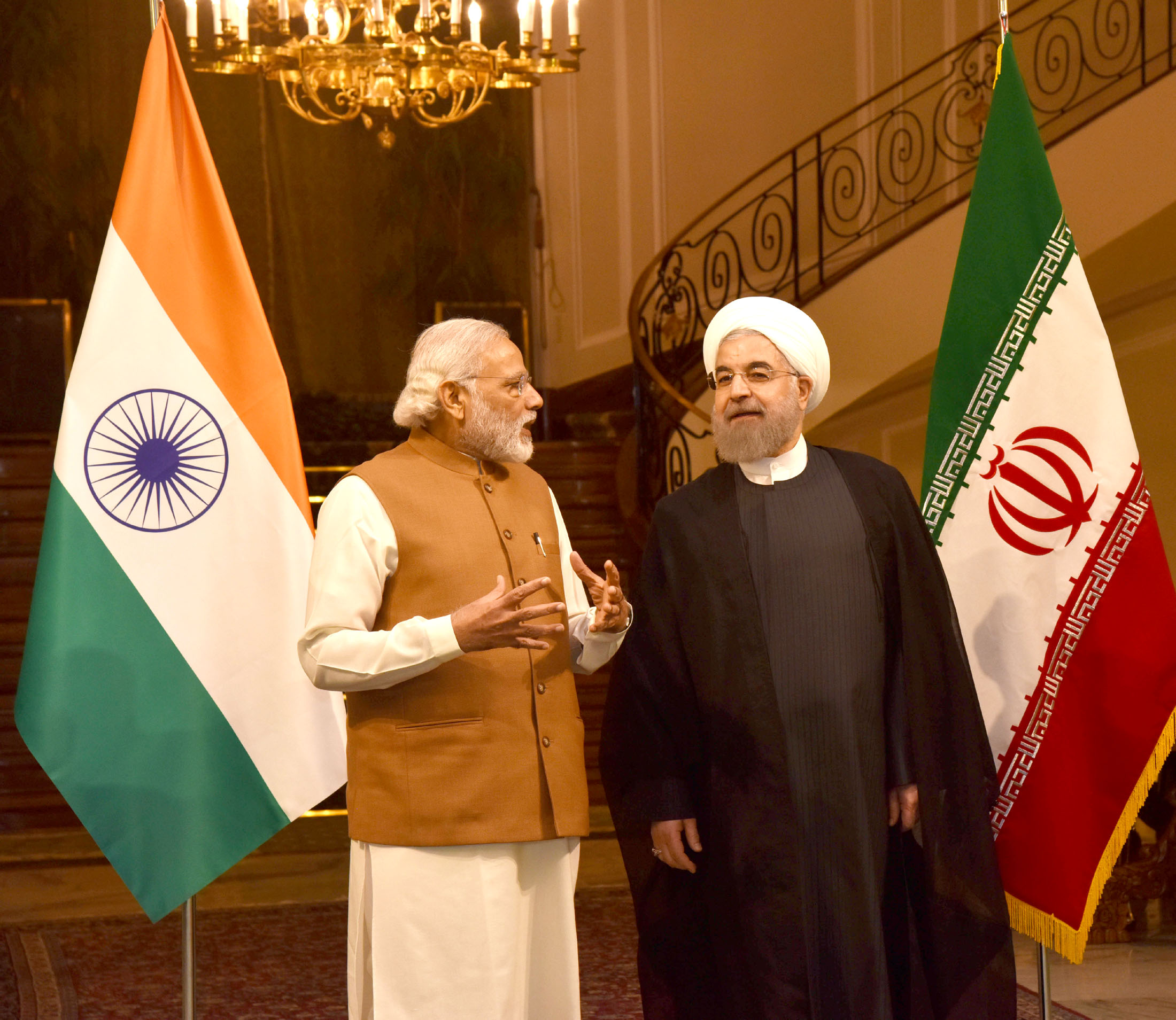Narendra Modi shaking hands with Iranian President Hassan Rouhani with Indian and Iranian flags behind them.