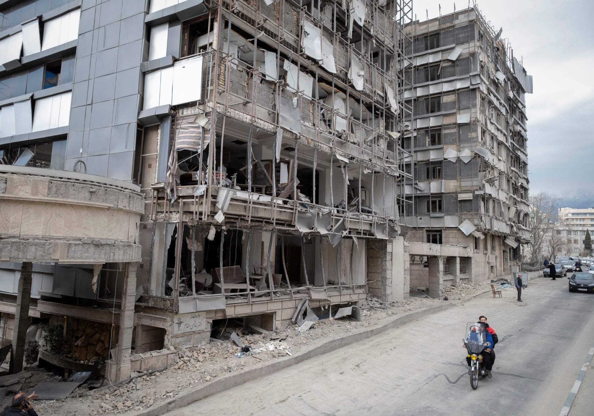 An Iranian motorcyclist rides past the Gandhi Hospital, which is damaged after US-Israeli strikes on a state TV telecommunication tower nearby in Tehran, Iran, on March 2, 2026.