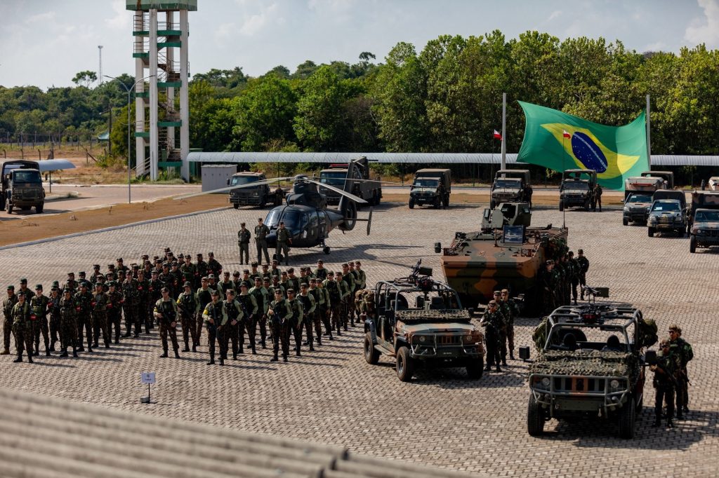 Brazilian soldiers stand alongside army equipment and vehicles