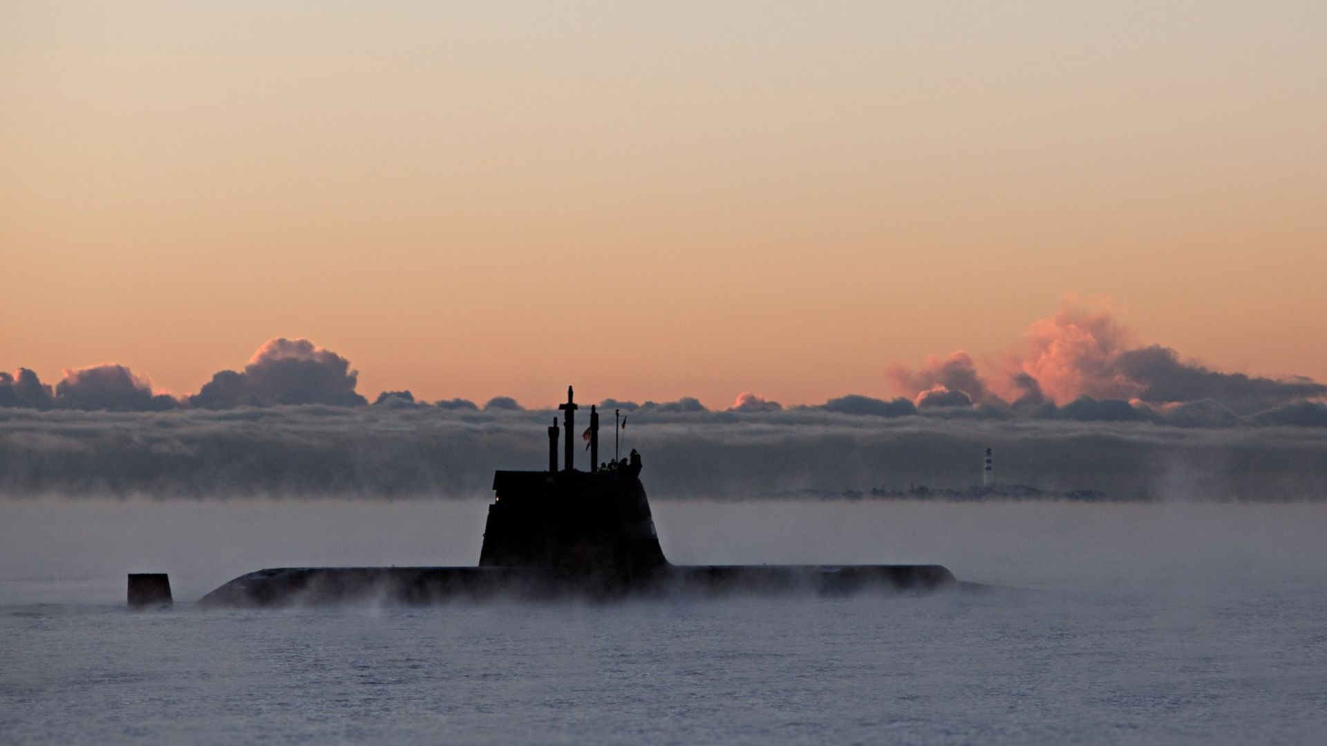 A military submarine emerges through dense sea mist under a dramatic orange dawn sky, used to illustrate Indra's development of a new satellite link to extend submarine connectivity at sea