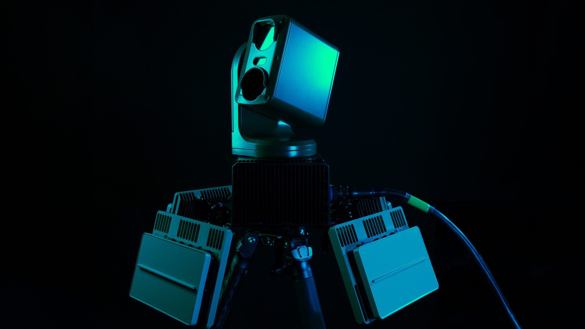Roke counter-drone system featuring a multi-sensor turret head and flanking electronics modules on a tripod mount against a dark background