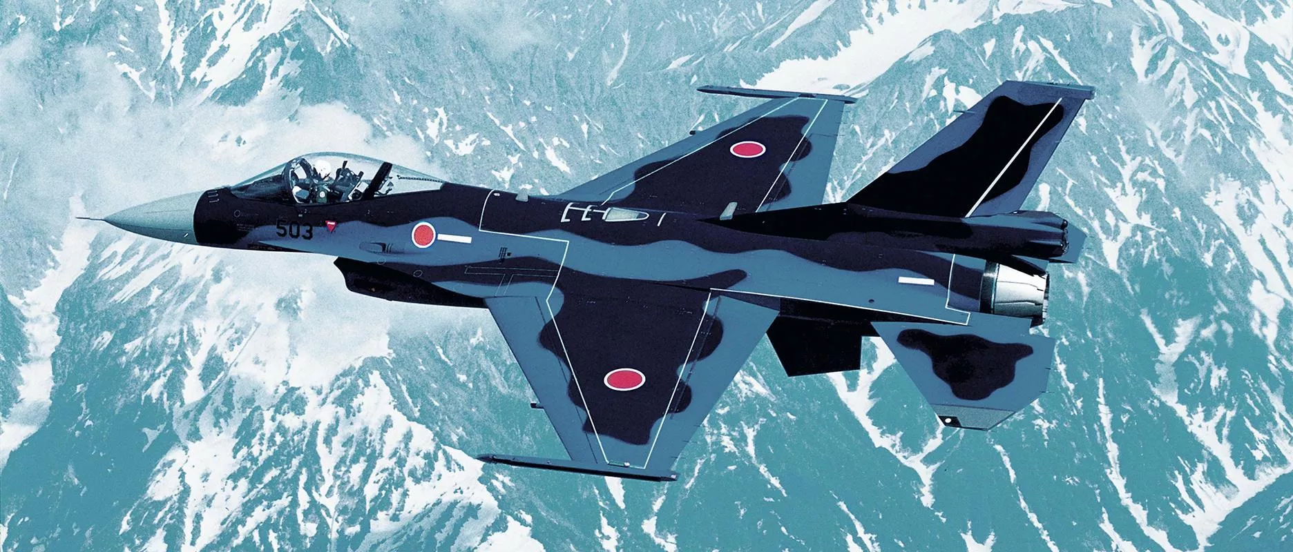 Japan Air Self-Defense Force F-2 fighter aircraft flying over snow-covered mountains.